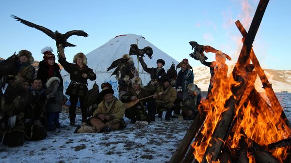 Lovci sa svojim pripitomljenim zlatnim orlovima i jastrebovima okupljaju se oko vatre tokom tradicionalnog takmičenja u lovu izvan sela Kajnar 8. decembra 2019. - Sputnik Srbija