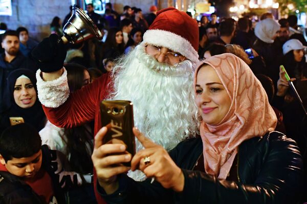 На божићној прослави у сиријској Латакији жена се фотографише са мушкарцем обученим као Деда Мраз. - Sputnik Србија