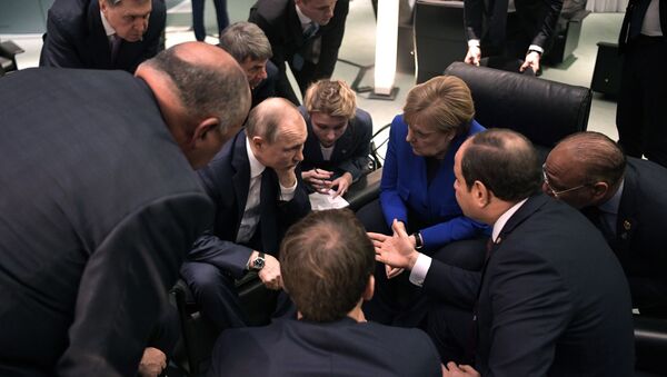 Predsednik Rusije Vladimir Putin i nemačka kancelarka Angela Merkel okruženi zvaničnicima na marginama konferencije o Libiji u Berlinu - Sputnik Srbija