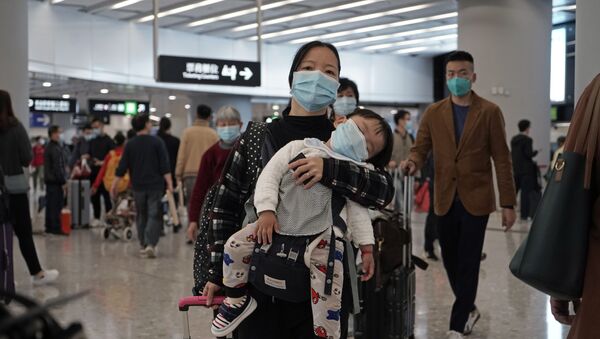 Putnici nose zaštitne maske za lice na ulazu železničke stanice u Hongkongu - Sputnik Srbija