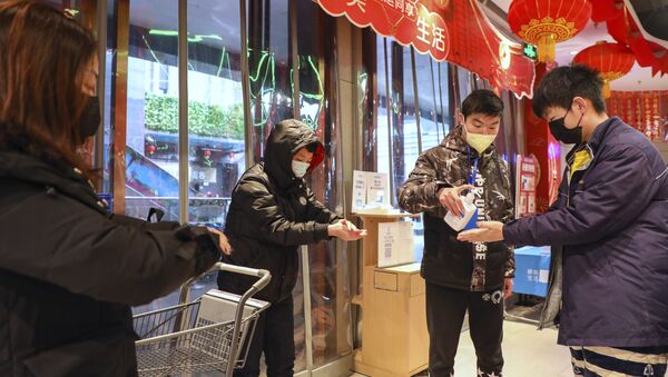 Људи дезинфикују руке на улазу у продавницу у кинеском граду Вухан - Sputnik Србија