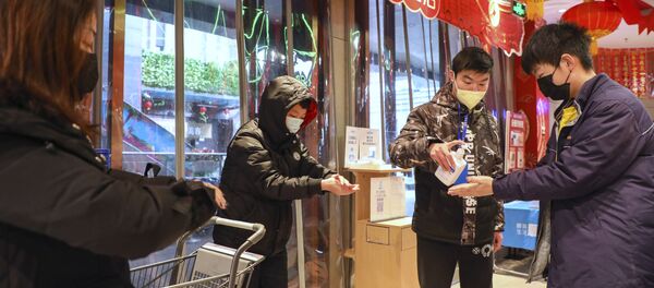 Ljudi dezinfikuju ruke na ulazu u prodavnicu u kineskom gradu Vuhan - Sputnik Srbija