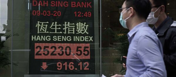 Човек са маском пролази поред берзанског дисплеја испред банке у Хонгконгу - Sputnik Србија