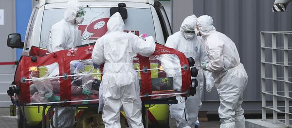 Медицинари у заштитној униформи премештају пацијента из амбулантних кола у болницу у Сеулу - Sputnik Србија