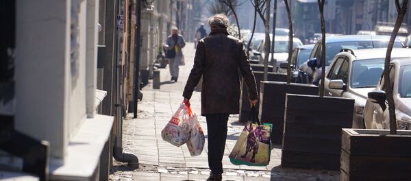 Жена са пуним торбама након куповине усред епидемије коронавируса - Sputnik Србија
