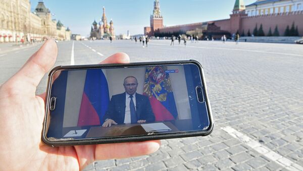 Московљанин на Црвеном тргу преко телефона прати обраћање председника Русије Владимира Путина - Sputnik Србија