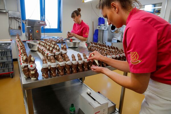 Припрема чоколадних ускршњих зека са заштитном маском у посластичарници у Швајцарској. - Sputnik Србија