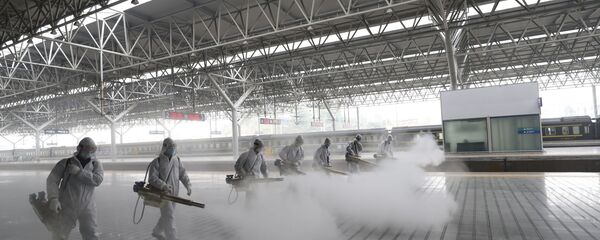 Радници у заштитним оделима дезинфикују платформу железничке станице у Јичангу у кинеској провинцији Хубеј. Кина је поново отворила неке железничке и аутобуске станице након укидања карантина у провинцији Хубеј - Sputnik Србија