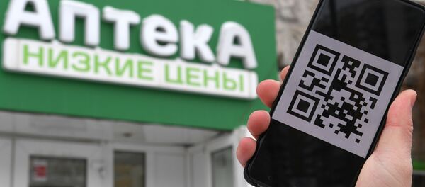 Čovek drži telefon sa kju-ar kodom. - Sputnik Srbija