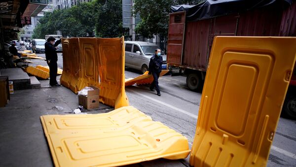 Pripadnici obezbeđenja sa maskama na licu uklanjaju barikade na ulici u Vuhanu, nakon što su kineske vlasti odblokirale ulazak u grad - Sputnik Srbija