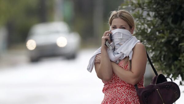 Žena čeka u redu da uđe u trgovinu i razgovara mobilnim telefonom sa košuljom omotanom oko lica, Florida. - Sputnik Srbija
