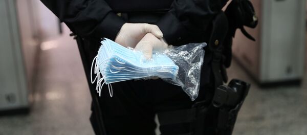 Полицајац држи заштитне маске за лице Полицајац држи заштитне маске за лице - Sputnik Србија
