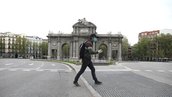 Човек са заштитном маском и рукавицама пролази поред пустог трга у Мадриду - Sputnik Србија