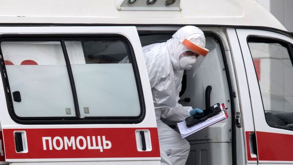Здравствени радник у заштитном оделу излази из возила хитне помоћи испред болнице у Москви - Sputnik Србија