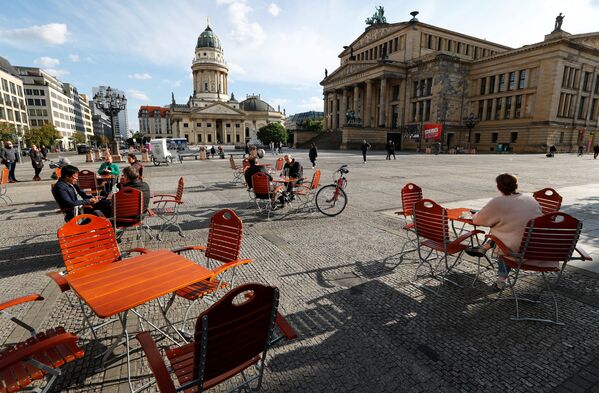 Ljudi uživaju u lepom vremenu u kafiću na trgu Gendarmenmarkt, gde se primenjuju mere fizičkog distanciranja za vreme epidemije virusa korona, u Berlinu, Nemačka, 16. maja 2020. godine. - Sputnik Srbija