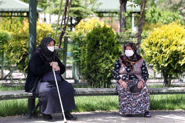 Starije žene, noseći zaštitne maske za lice, sede na klupi parka u okrugu Akijurt, jer je osobama starijim od 65 godina i pacijentima sa hroničnim bolestima širom Turske dozvoljeno da napuštaju svoje domove, poštuju određenu udaljenost i nose maske između 12 i 18 časova po lokalnom vremenu, u Ankari 17. maja 2020. godine. - Sputnik Srbija