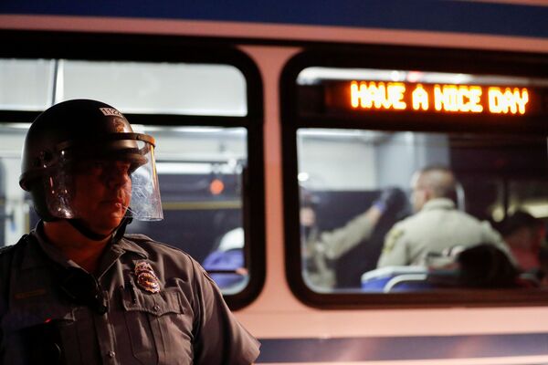 Policajac stoji ispred autobusa tokom protesta usred nemira u zemlji nakon smrti Afroamerikanca Džordža Flojda u Mineapolisu. - Sputnik Srbija