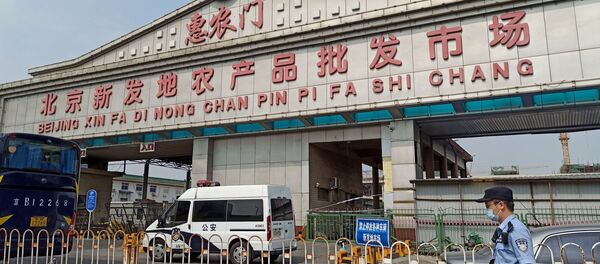 Полицајац са заштитном маском испред улаза у пијацу Синфади у Пекингу, која је затворена након избијања нове инфекције вируса корона - Sputnik Србија