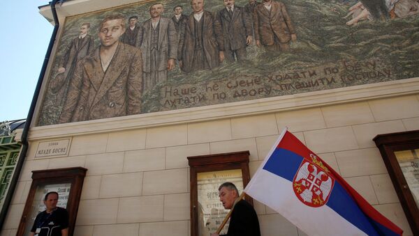 Човек носи српску заставу, пролазећи поред зграде на којој је мозаик Гаврила Принципа - Sputnik Србија
