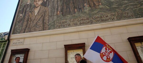 Човек носи српску заставу, пролазећи поред зграде на којој је мозаик Гаврила Принципа - Sputnik Србија