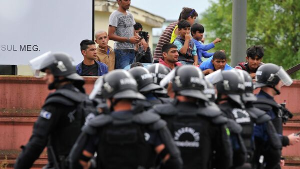 Полиција  стоји на улазу у  избеглички камп у Дебрецину, 230 километара од Будимпеште, Мађарска, понедељак, 29. јуна, 2015. - Sputnik Србија
