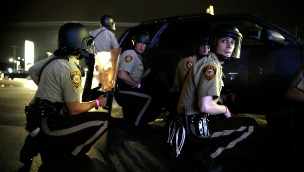 Police take cover behind a vehicle during a protest in Ferguson, Mo., Sunday, Aug. 9, 2015 - Sputnik Србија