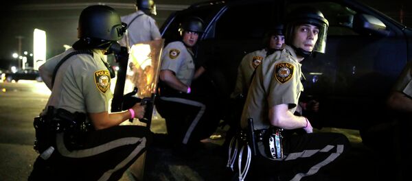 Police take cover behind a vehicle during a protest in Ferguson, Mo., Sunday, Aug. 9, 2015 Police take cover behind a vehicle during a protest in Ferguson, Mo., Sunday, Aug. 9, 2015 - Sputnik Србија