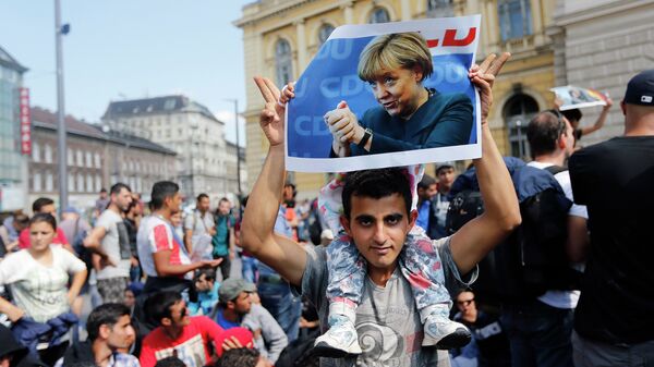 Izbeglice u Budimpešti sa posterima nemačke kancelarke Angele Merkel - Sputnik Srbija