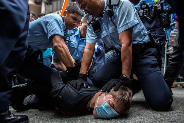 Policajci hapse protestanta u Honkongu. - Sputnik Srbija