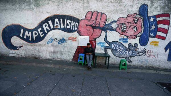 Човек седи поред графита на ком пише империјализам и издајник. Каракас, 9. март 2015. - Sputnik Србија